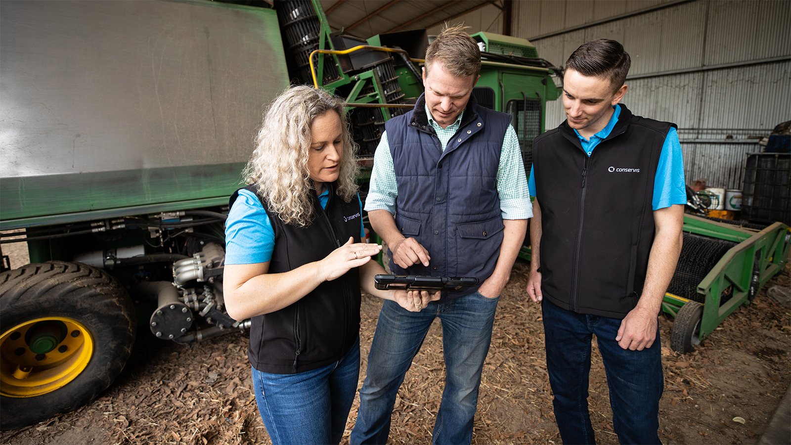 Conservis Customer Success standing with a customer on farm performing services with a tablet